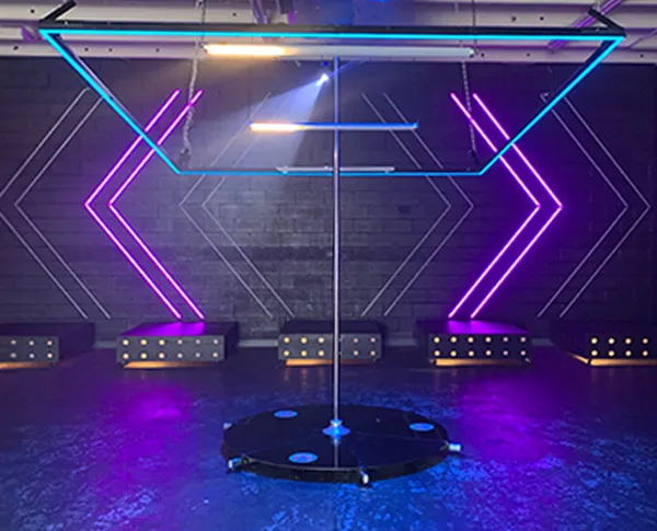 Lupit pole stage with neon purple and cyan stage lighting in a low-lit venue